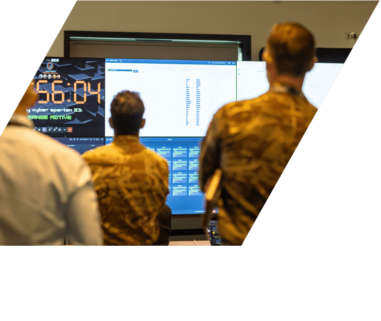 3 people in military uniform and shirts looking at screens at event