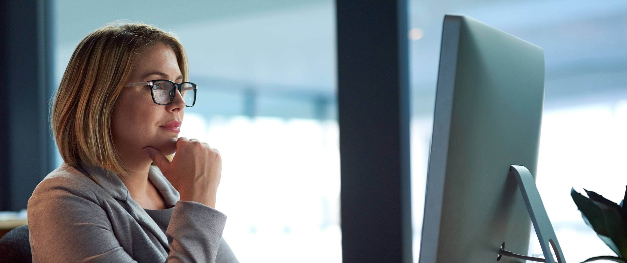 Focused woman in suit looking at computer screen