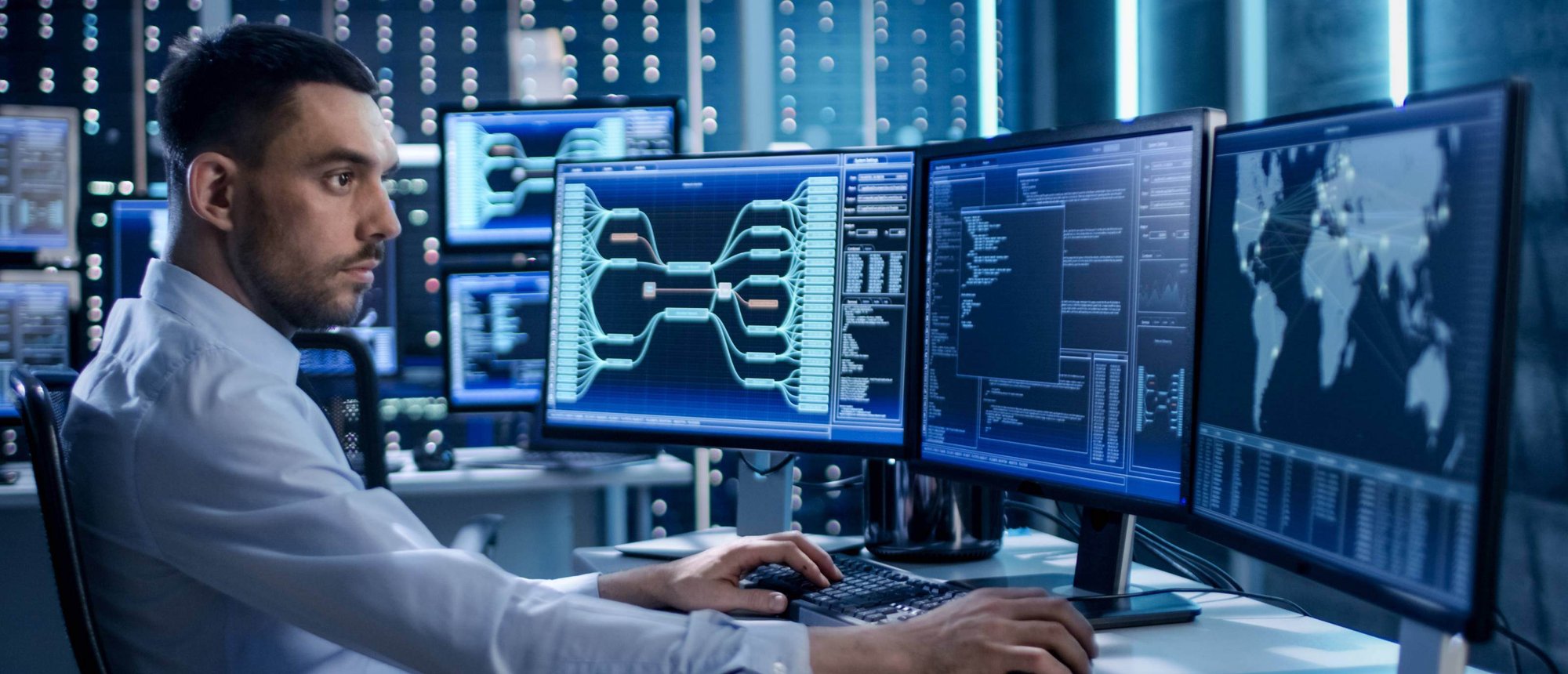 Man in shirt looking at data on computer screens