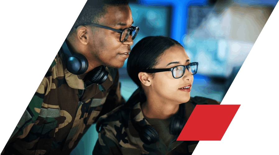 Woman and man in camo uniform looking and pointing at computer screen