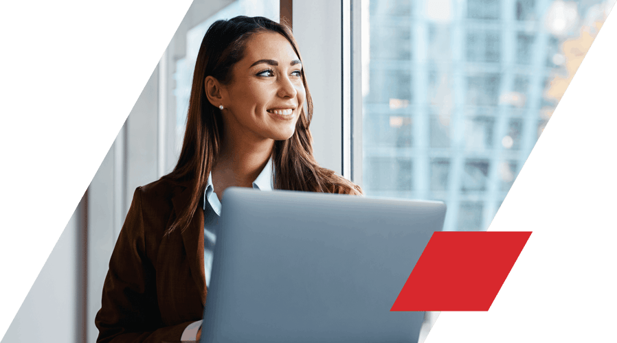 Woman in jacket holding laptop and smiling looking out of window