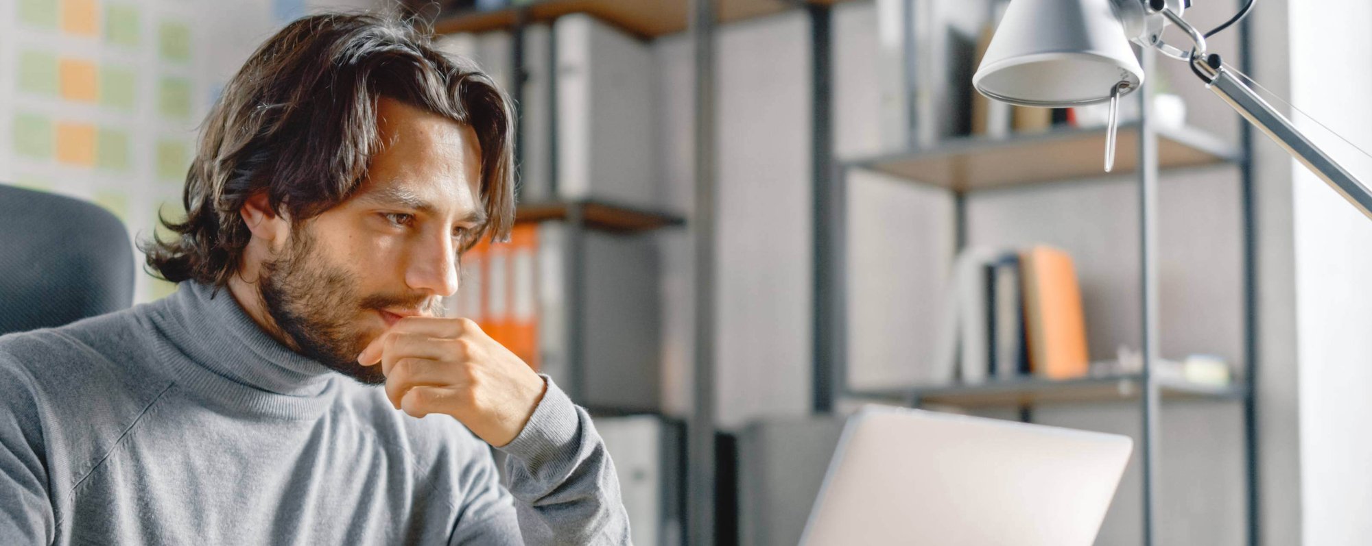 Thoughtful man in office looking at laptop