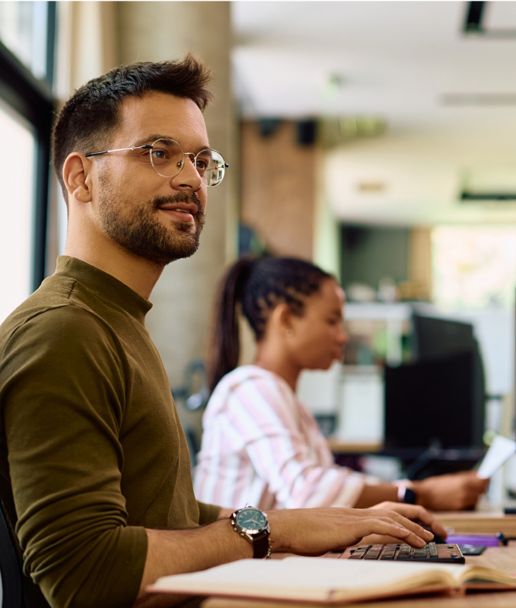 Man with glasses looking at computer screen with woman in background-mobile