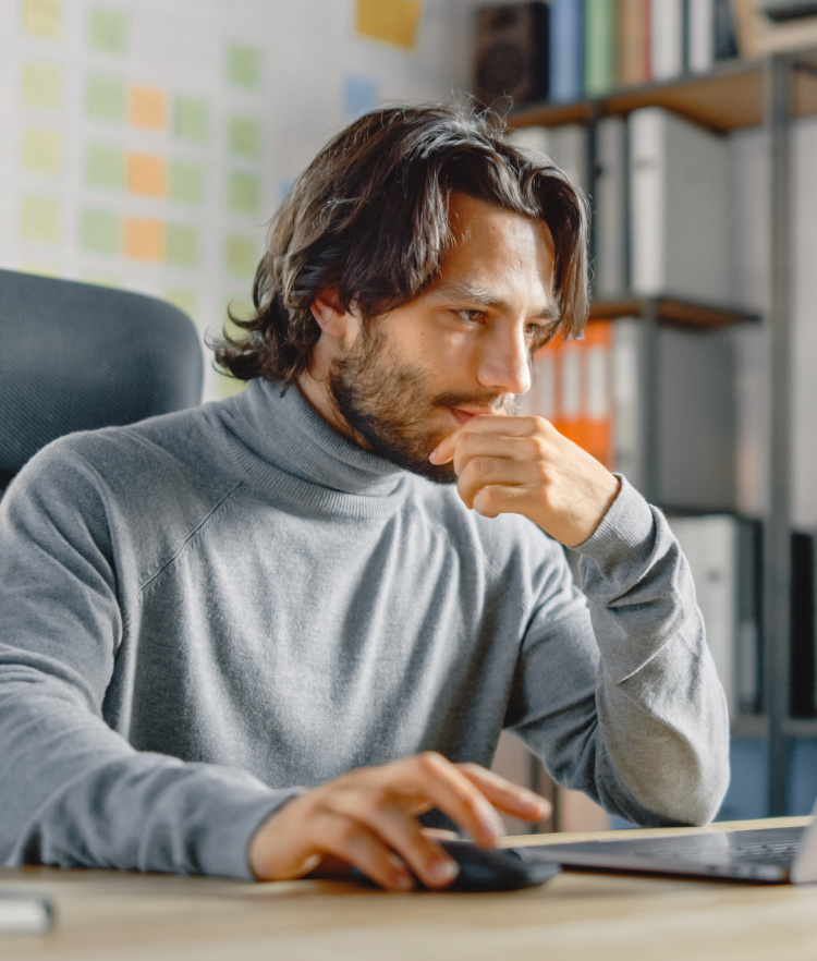 Thoughtful man in office looking at laptop-mobile